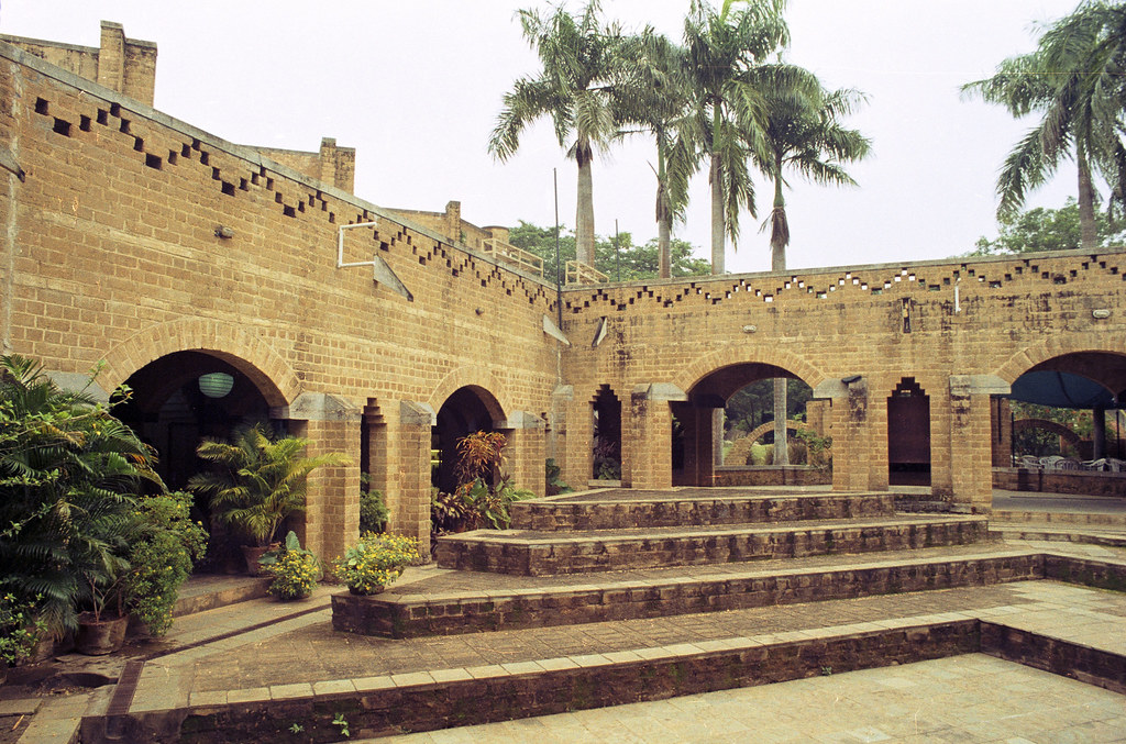 A red brick walled building with trees in the background.