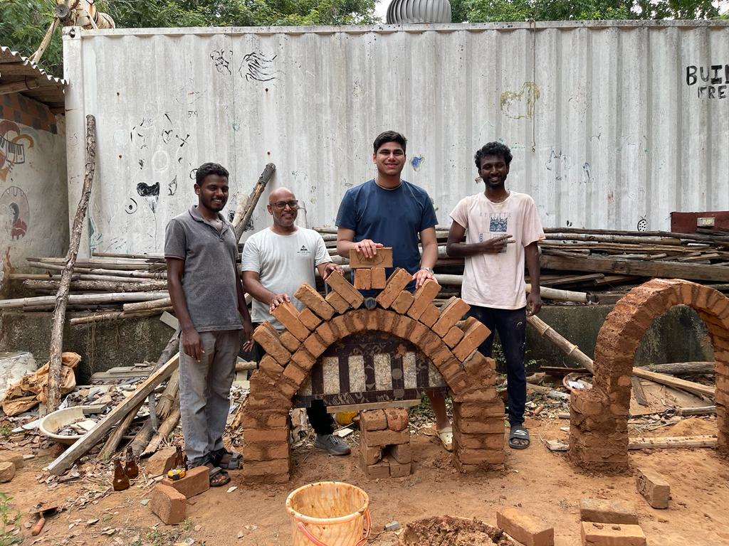 Four people standing with a brick structure