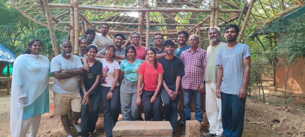 People standing in front of bamboo house for a photo.