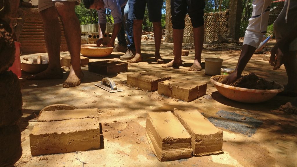Freshly made bricks drying in the sun with people standing around.